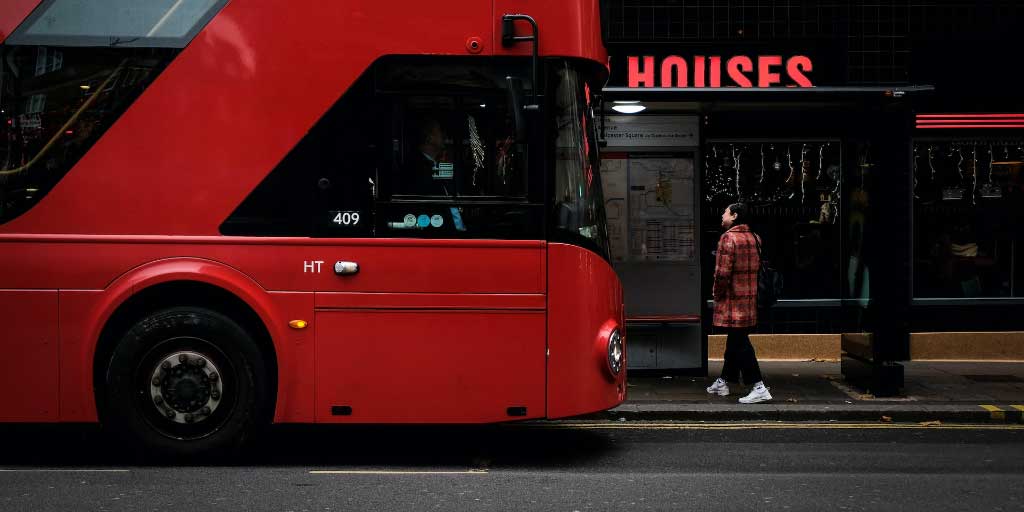 punainen bussi pysähtyneenä bussipysäkille