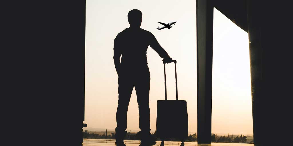 Mies seisoo matkalaukun kanssa lentokentällä