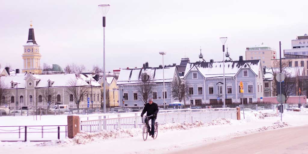 mies pyöräilee talvella oulun kadulla
