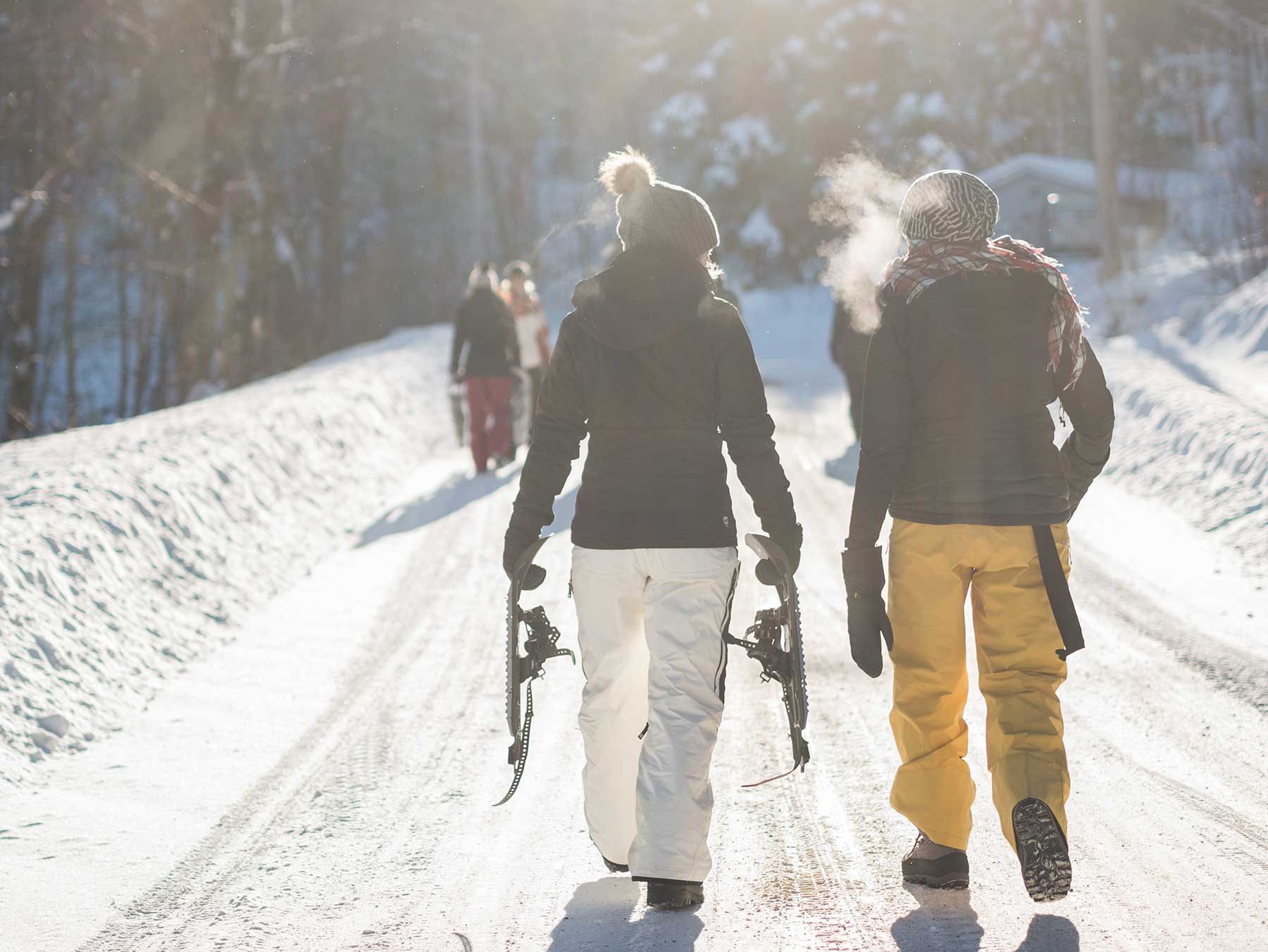 Kaksi henkilöä kävelee lumisella tiellä